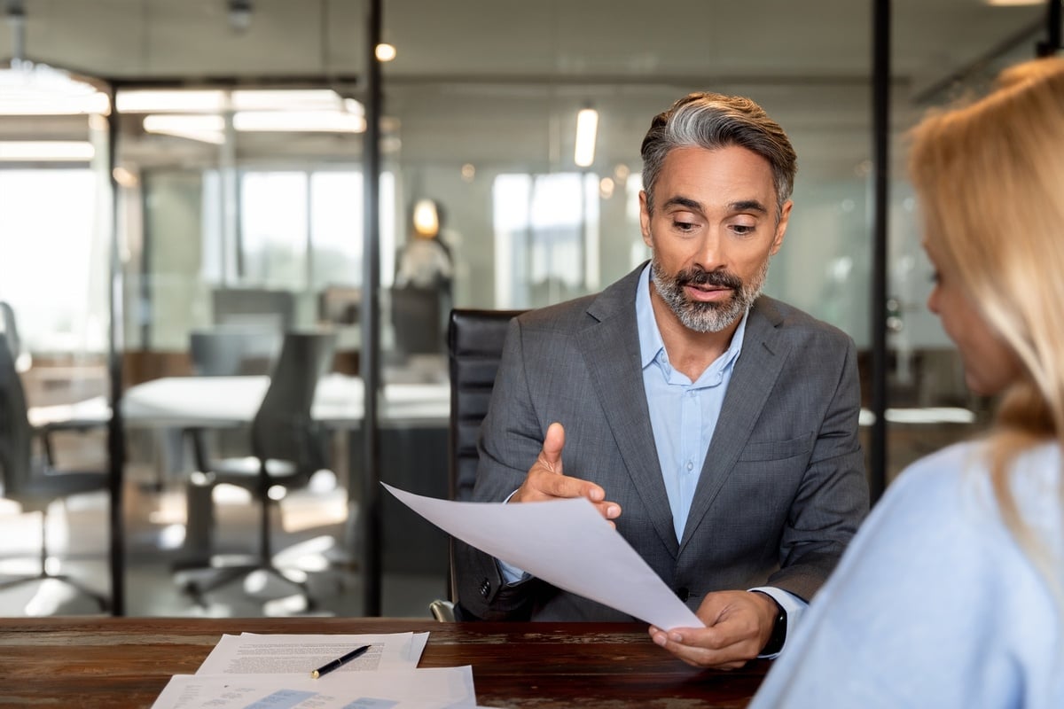 A man in a suit reviewing papers with someone