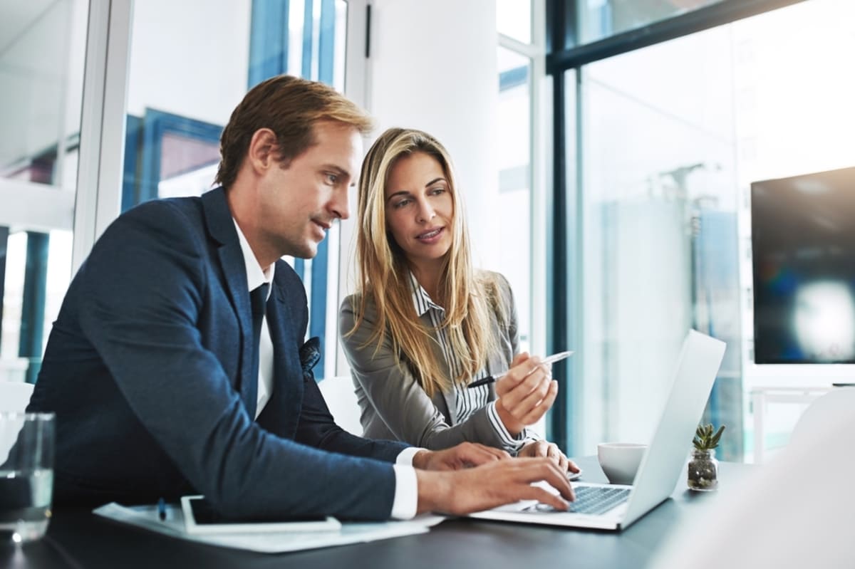 Man and woman talk about information on a laptop, property management consulting services concept